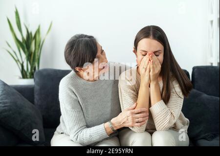 Una madre amorosa più anziana sostiene la figlia adulta depressa, la mamma matura cura abbraccio triste piangendo giovane donna, conforto e carezza bambino cresciuto a. Foto Stock