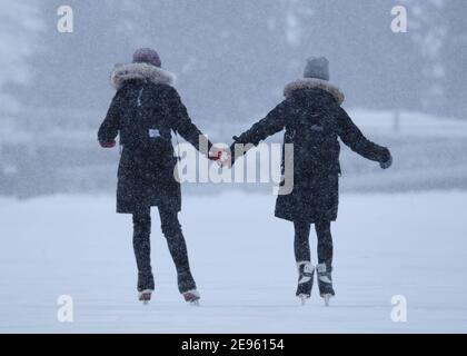 Ottawa, Canada. 2 Febbraio 2021. Duo che tiene le mani indossando una foglia d'acero mitens mentre pattina Foto Stock