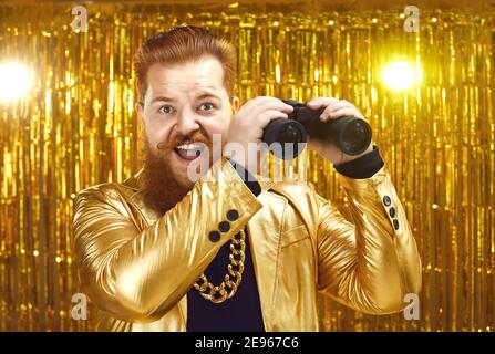 Uomo divertente che tiene binocoli e guardando a distanza con sorpreso guarda in faccia Foto Stock