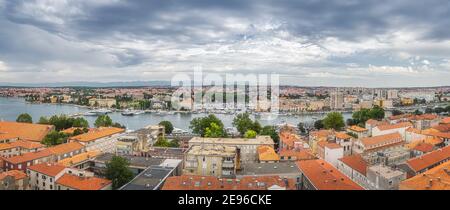 Ampio panorama con vista a volo di droni o uccelli sui tetti di tegole arancioni e il paesaggio urbano di Zara. Baia o marina con yacht ormeggiati e barche, Croazia Foto Stock