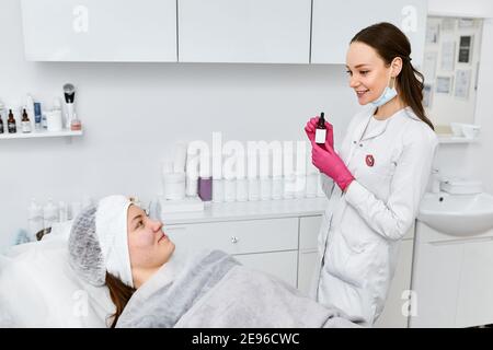 Beautician effettua iniezioni di mesoterapia, trattamenti di bellezza, cura della pelle. Donna che si cura del viso da estetista al salone termale, vista laterale. Centro benessere Foto Stock