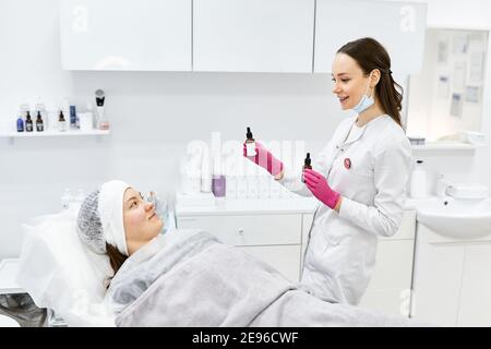 Beautician effettua iniezioni di mesoterapia, trattamenti di bellezza, cura della pelle. Donna che si cura del viso da estetista al salone termale, vista laterale. Centro benessere Foto Stock