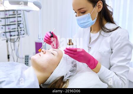 Beautician effettua iniezioni di mesoterapia, trattamenti di bellezza, cura della pelle. Donna che si cura del viso da estetista al salone termale, vista laterale. Centro benessere Foto Stock