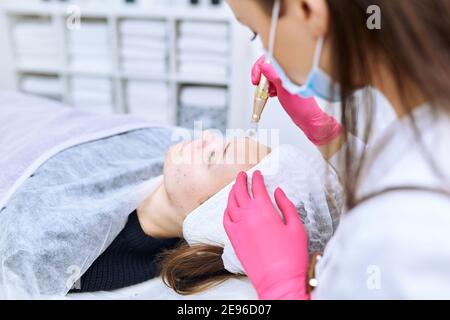 Beautician effettua iniezioni di mesoterapia, trattamenti di bellezza, cura della pelle. Donna che si cura del viso da estetista al salone termale, vista laterale. Centro benessere Foto Stock