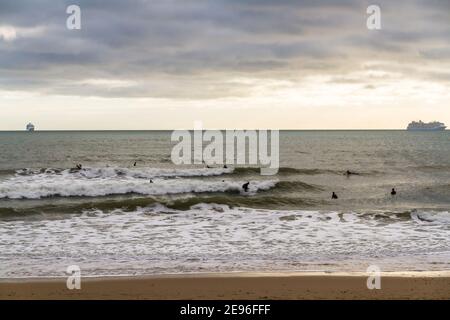 BOURNEMOUTH, INGHILTERRA - GENNAIO 17 2021: Due navi da crociera ormeggiate al largo di Bournemouth a Poole Bay, surfisti in paesaggio marino Foto Stock