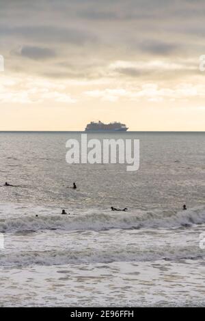 BOURNEMOUTH, INGHILTERRA - GENNAIO 17 2021: Nave da crociera ormeggiata al largo di Bournemouth a Poole Bay, surfisti in ritratto di mare Foto Stock