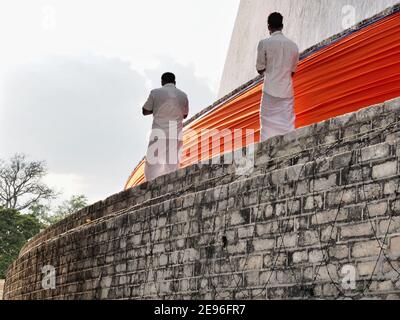 ANURADHAPURA, SRI LANKA - 9 marzo 2019: Due uomini pregano sul tempio di Ruwanwelisaya nella città sacra di Anuradhapura. Foto Stock