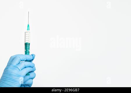 Una mano del medico in un guanto medico contiene una siringa con un ago per proteggere contro il virus dell'influenza. Vaccino CVD. Il concetto di vaccinazione medica Foto Stock