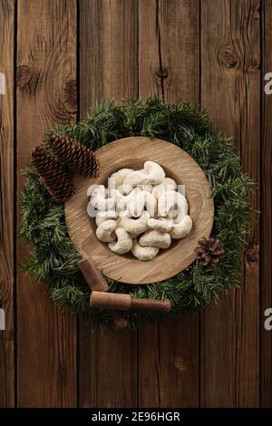 Pasticceria tedesca di Natale vanillekipferl. Biscotti a forma di mezzaluna in zucchero a velo in piastra di quercia su corona di abete su rustico vecchio fondo di legno Foto Stock