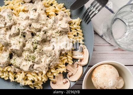 Tagliatelle con salsa cremosa ai funghi di champignon bianchi della foresta e pollo o carne di manzo - cibo fatto in casa in piatto sulla vista dall'alto del tavolo Foto Stock