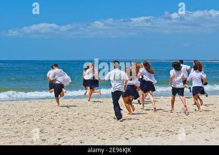 La scuola è fuori. Il loro ultimo giorno di scuola - gli studenti delle scuole superiori nelle loro uniformi scolastiche che corrono tradizionalmente nell'oceano Foto Stock