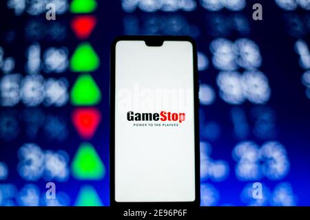 In questa illustrazione fotografica viene visualizzato un logo GameStop su uno smartphone con i numeri in maiuscolo sullo sfondo. Foto Stock