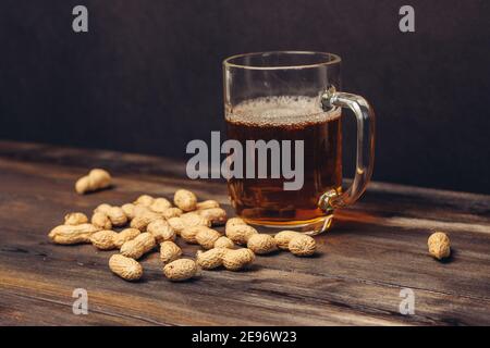 tazza di birra su un tavolo di legno arachidi in conchiglie primo piano su bevande alcoliche Foto Stock