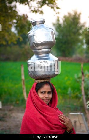 TIKAMGARH, MADHYA PRADESH, INDIA - 23 GENNAIO 2021: Una donna indiana che porta un contenitore d'acqua sulla testa. Foto Stock