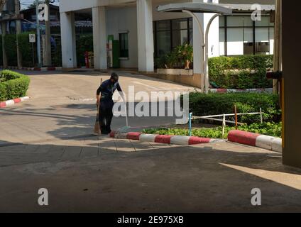 Bangkok, Thailandia - 2 febbraio 2021 : UNA operatrice femminile sta pulendo il pavimento usando scopa e casseruola, la scopa è in movimento sfocato Foto Stock