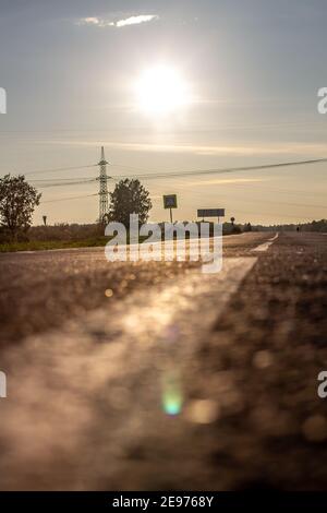 Una lunga striscia bianca, come un pennarello stradale. Una strada nella distanza tra i campi e le foreste. Foto di alta qualità Foto Stock