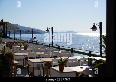 Caffetteria all'aperto con una vista elegante della baia, tavolo e sedie in legno Seaside, caffetteria all'aperto, ristorante all'aperto a Marina Bay, Bodrum - Turchia, sulla riva del mare Foto Stock