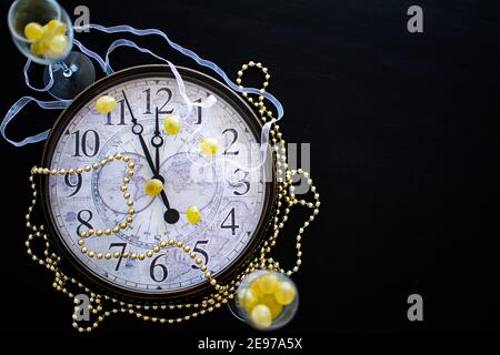 un orologio faccia circa per colpire la mezzanotte nei nuovi anni vigilia in Spagna con due flauti di champagne con dodici uve Foto Stock