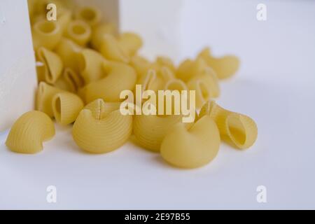 Pasta italiana di grano duro versata da scatola bianca sul tabella Foto Stock