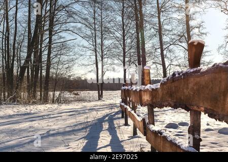 Recinzione in legno in un paesaggio rurale invernale. Strada di campagna invernale. Febbraio polacco a Mazovia. Viaggio in Europa. Alberi tra campi innevati. Foto Stock