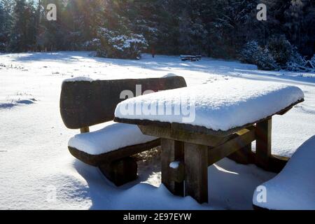 Gruppo di tavoli ricoperti da uno spesso strato di neve fresca composto da un tavolo e due panche su un riposo Zona nel paesaggio brughiera vicino Luneburg in nort Foto Stock