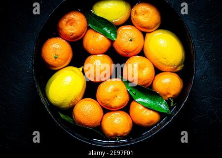 Raccolta degli agrumi: Mandarini e limoni. Sfondo di agrumi. Foto Stock