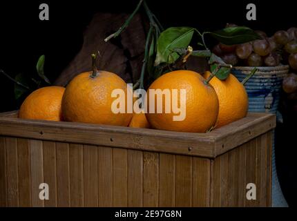 Arance fresche nel cesto di legno con foglie verdi. Foto Stock