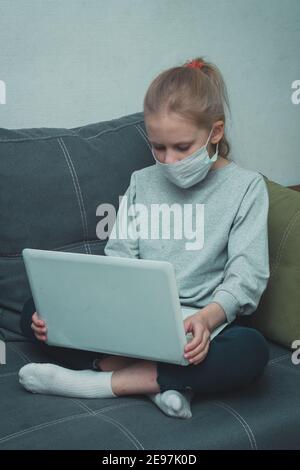 maschera studentessa guarda le lezioni video sul computer portatile in quarantena Foto Stock