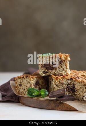 Piazze di farinata d'avena con cioccolato, fondo di cemento chiaro. Dieta bar. Panetteria sana per colazione o dessert. Messa a fuoco selettiva. Foto Stock