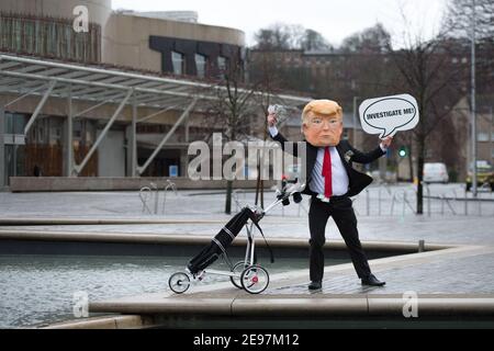 Edimburgo, Scozia, Regno Unito. 3 febbraio 2021. Nella foto: In vista di un dibattito e di un voto al Parlamento scozzese per decidere se il governo scozzese dovrebbe indagare sul finanziamento dei campi da golf scozzesi da parte di Donald Trump, gli attivisti ritrarranno un falso Trump che indossa una testa gigante, una cravatta rossa e porta un cartello con la scritta "Incolosimi!" Al di fuori del Parlamento scozzese. Inoltre trascinerà il suo sacchetto di golf che traboccola con le fatture del dollaro. Credit: Colin Fisher/Alamy Live News Foto Stock