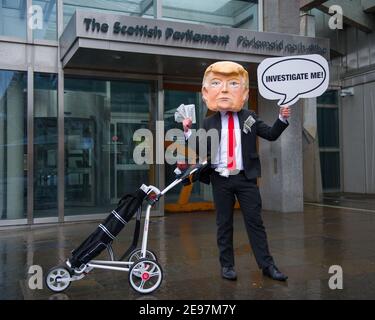 Edimburgo, Scozia, Regno Unito. 3 febbraio 2021. Nella foto: In vista di un dibattito e di un voto al Parlamento scozzese per decidere se il governo scozzese dovrebbe indagare sul finanziamento dei campi da golf scozzesi da parte di Donald Trump, gli attivisti ritrarranno un falso Trump che indossa una testa gigante, una cravatta rossa e porta un cartello con la scritta "Incolosimi!" Al di fuori del Parlamento scozzese. Inoltre trascinerà il suo sacchetto di golf che traboccola con le fatture del dollaro. Credit: Colin Fisher/Alamy Live News Foto Stock