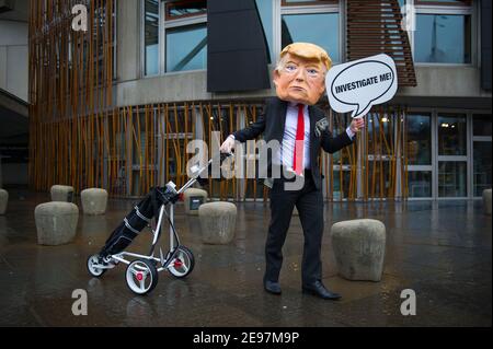 Edimburgo, Scozia, Regno Unito. 3 febbraio 2021. Nella foto: In vista di un dibattito e di un voto al Parlamento scozzese per decidere se il governo scozzese dovrebbe indagare sul finanziamento dei campi da golf scozzesi da parte di Donald Trump, gli attivisti ritrarranno un falso Trump che indossa una testa gigante, una cravatta rossa e porta un cartello con la scritta "Incolosimi!" Al di fuori del Parlamento scozzese. Inoltre trascinerà il suo sacchetto di golf che traboccola con le fatture del dollaro. Credit: Colin Fisher/Alamy Live News Foto Stock