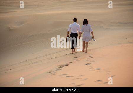Coppia che cammina lungo la sabbia bianca sulla spiaggia Foto Stock