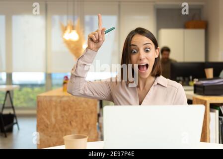 Ha ispirato una donna ispanica che ha un'idea mentre guarda il suo laptop in ufficio. Foto Stock