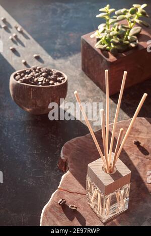 Deodorante per ambienti con bastoncini di bambù con profumo in vetro su sfondo scuro testurizzato. Rinvigorente odore di caffè. Sfondo scuro. Chicchi di caffè arrosto Foto Stock