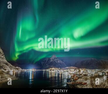 Aurora boreale sul cielo stellato visto sopra il villaggio di Reine sulle isole Lofoten. Notte invernale con incredibili luci verdi. Foto Stock