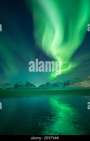 Aurora boreale sopra le montagne delle isole Lofoten. Riflessioni di Aurora Borealis sulla spiaggia sabbiosa di Sandbotnen. Belle condizioni invernali a nort Foto Stock