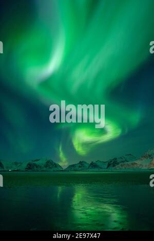 Aurora boreale sopra le montagne delle isole Lofoten. Riflessioni di Aurora Borealis sulla spiaggia sabbiosa di Sandbotnen. Belle condizioni invernali a nort Foto Stock