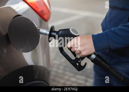 Primo piano delle mani dell'uomo che pompano benzina combustibile in automobile alla stazione di benzina. Benzina o benzina che viene pompata in un'automobile di automobile. Foto Stock