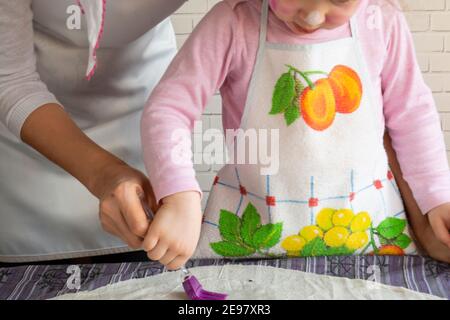 Donna e bambina che lubrificano l'impasto grezzo posato sul tavolo con un pennello Foto Stock