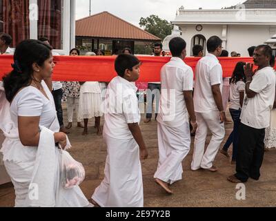 ANURADHAPURA, SRI LANKA - 9 marzo 2019: I pellegrini portano un panno arancione lungo e infinito da offrire Foto Stock