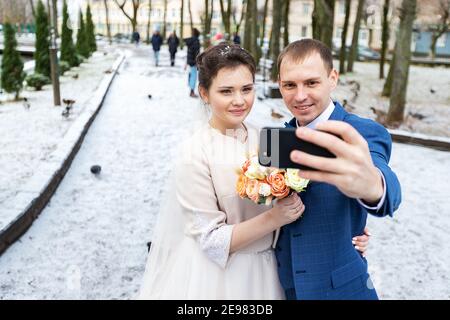 due sposi novelli in una passeggiata di nozze in inverno, gli amanti felicemente abbraccio e delicatamente bacio, due adulti in una data Foto Stock