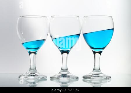 tre bicchieri di vino riempiti di fluido blu fianco a fianco Foto Stock