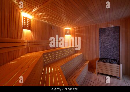 Posto a sedere nella sala sauna. Vuoto bagno turco in legno con pietra heater.Sauna stanza per una buona salute. Sala sauna con accessori per sauna tradizionali. Foto Stock