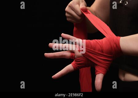 Muay Thai femmina boxer con cinturino da polso closeup vista. Fitness giovane donna che si prepara per l'allenamento di boxe su sfondo nero Foto Stock