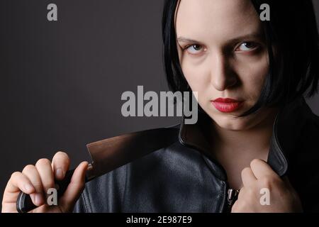 donna giovane seria con coltello che guarda il ritratto di closeup della macchina fotografica Foto Stock