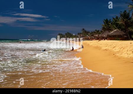 Hikkaduwa, Sri Lanka - 9 dicembre. 2010: Vista sulla spiaggia tropicale con palme e onde di mare ruvido Foto Stock