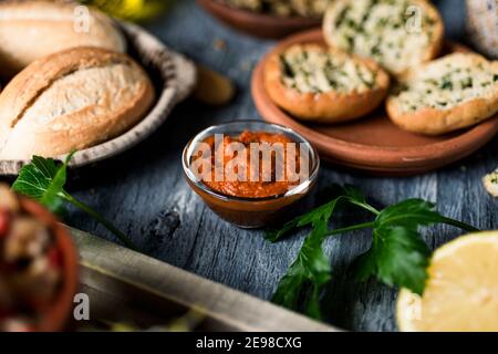 una ciotola di vetro con una versione vegana della tipica sobrasada spagnola, fatta con patata dolce rossa, su un tavolo in legno rustico grigio accanto ad alcune diverse k. Foto Stock