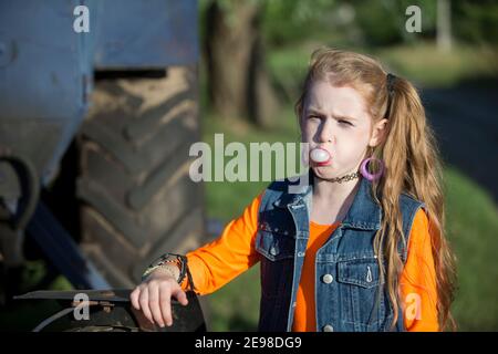 Una bambina in abiti luminosi ha fatto esplodire una bolla di gomma. Foto Stock