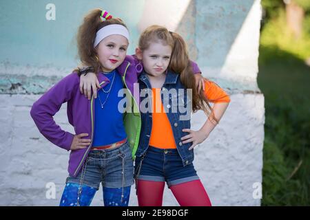 Due sono ragazze piccole divertenti con trucco luminoso vestito nello stile degli anni novanta. Foto Stock